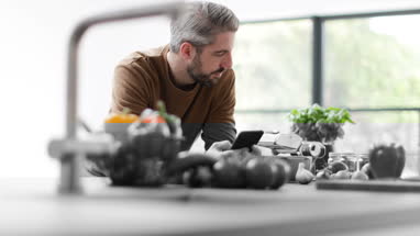 Adult male looking up recipe on smartphone in kitchen