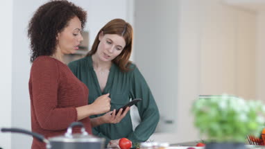 Friends looking at recipe on smartphone whilst cooking