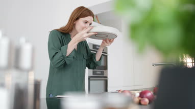 Adult female putting dish in oven