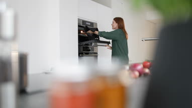 Adult female taking dish out of oven
