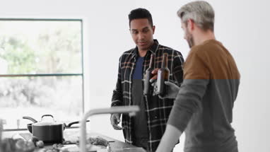 Male friends having a beer whilst cooking a meal