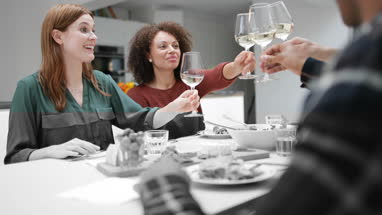 Friends clinking glasses over a meal together