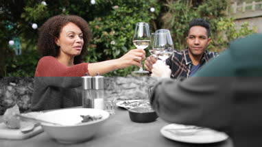 Friends eating a meal and drinking wine outdoors
