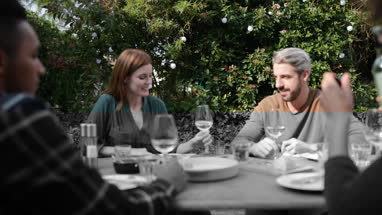 Adult female pouring a glass of wine at a meal with friends