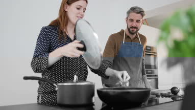 Couple tasting food whilst cooking