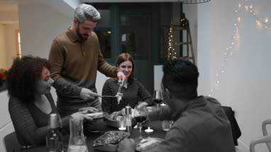 Adult male serving Christmas meal to friends
