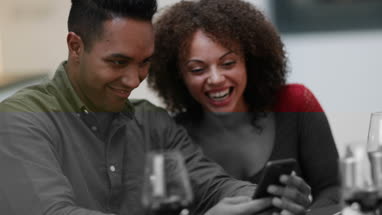 Couple looking at smartphone together at a meal