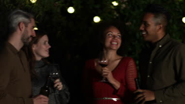 Friends drinking wine outdoors at night