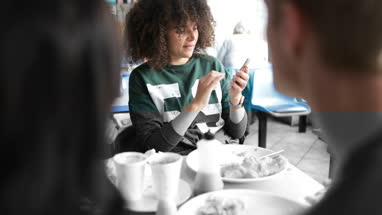 Young adult female showing friends photo on smartphone