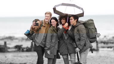 Group of young adult friends taking a selfie on a beach in winter