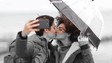 Young couple taking a selfie kissing on a winter break