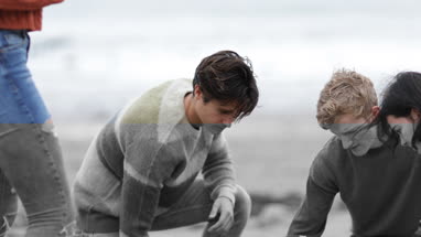 Friends building a campfire together on beach