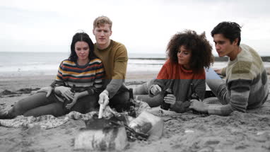 Group of young adult sitting around fire on winter break