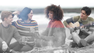 Group of young adult sitting around campfire socialising