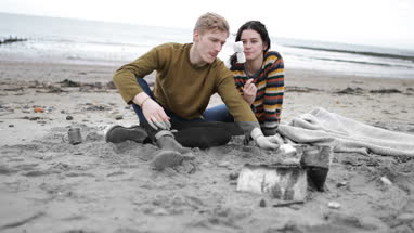 Young couple toasting marshmallows on camp fire