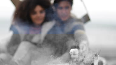 Young couple toasting marshmallows on camp fire