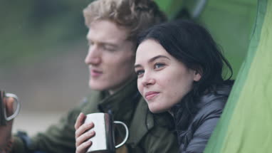 Young couple camping on the beach in fall