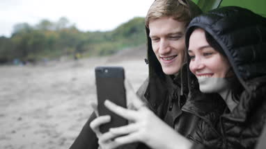 Young couple using a smartphone on a camping trip