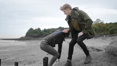 Boyfriend helping girlfriend climb a rock