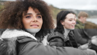 Group of young friends sitting on a wall looking  at view