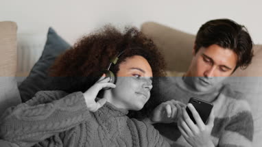 Couple at home listening to music on smartphone