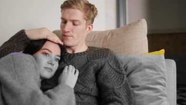 Couple at home cuddling on sofa