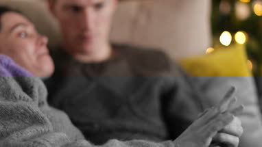 Couple at home cuddling on sofa at Christmas