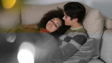 Couple at home cuddling on sofa at Christmas