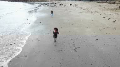 Aerial shot of friends running along beach 
