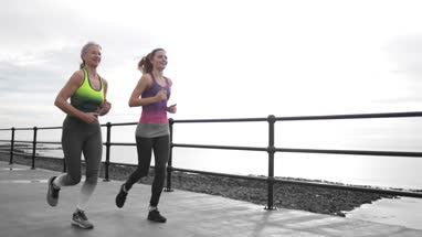Senior couple jogging to coastline