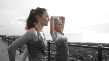 Active senior woman running with daughter on beach