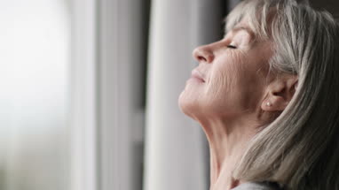 Senior woman looking out of window thinking