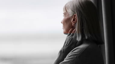 Senior woman looking out of window thinking
