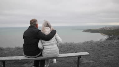 Senior couple sitting on a bench looking at sea view