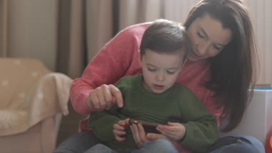 Preschool boy playing with smartphone with Mother