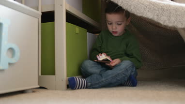 Preschool boy playing with smartphone in den