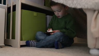 Preschool boy playing with smartphone in den