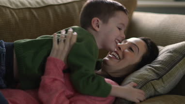 Mother tickling Son on sofa