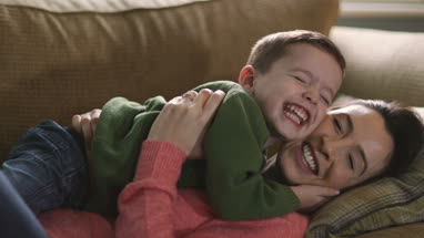 Mother tickling Son on sofa
