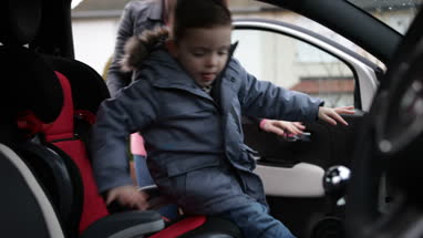 Mother putting Son in car seat safely
