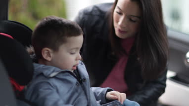 Mother putting Son in car seat safely