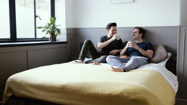 Young male couple relaxing with breakfast in bed