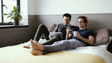 Young male couple using smartphone and digital tablet