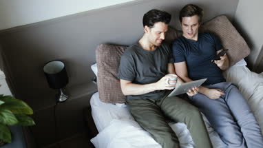 Overhead shot of young male couple using smartphone and digital tablet