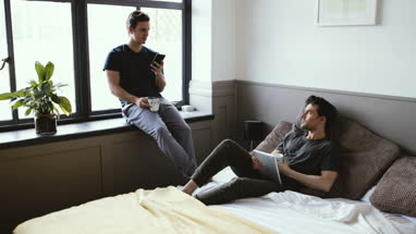 Young male couple on personal devices