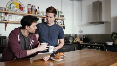 Young male couple looking at digital tablet in kitchen