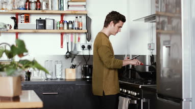 Young male cooking in kitchen using smartphone