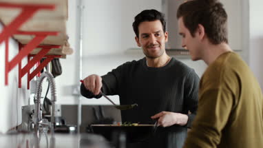 Young male couple cooking in kitchen