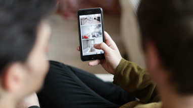 Young male couple looking for a home on smartphone app