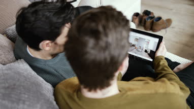 Young male couple looking for a home on digital tablet